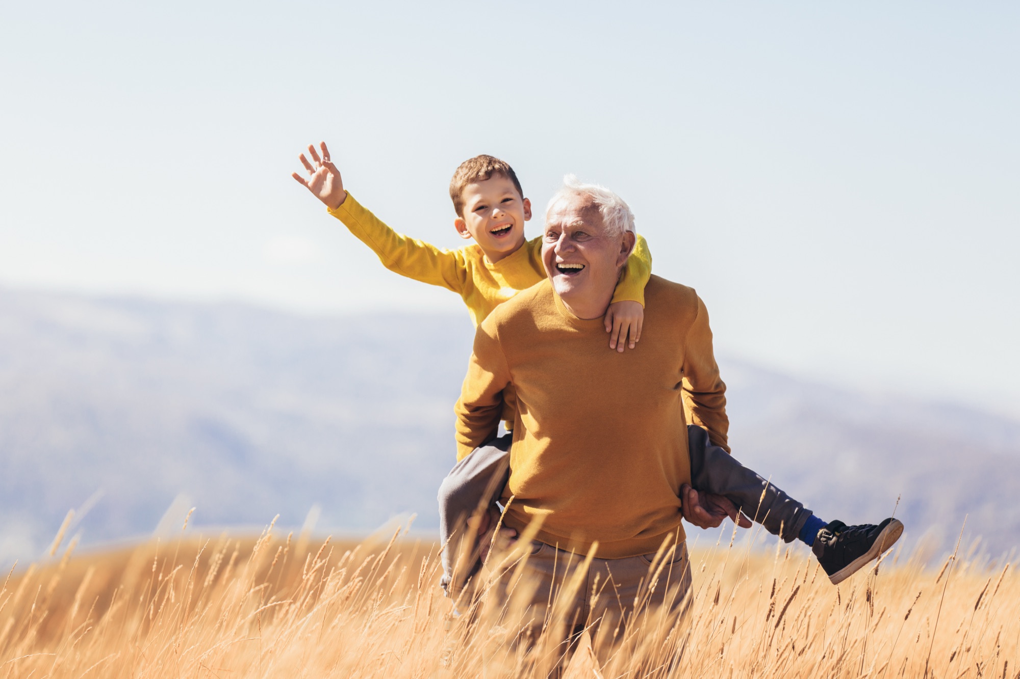 Grandfather and grandson laughing in a sunlit field